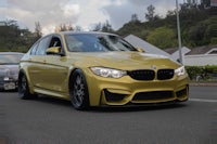 a yellow bmw m3 is parked on the street
