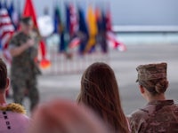 a group of military men and women are standing in front of flags