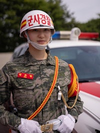 a woman in uniform standing next to a police car
