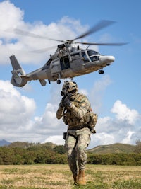 a soldier is walking in front of a helicopter