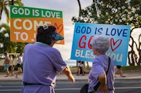 two women holding signs that say god is love