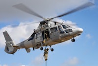 a helicopter with a man on a rope hanging from it