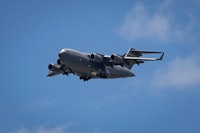 a large military jet flying through a blue sky