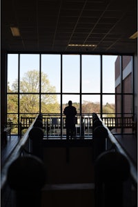 a person sitting on a stairway looking out a window